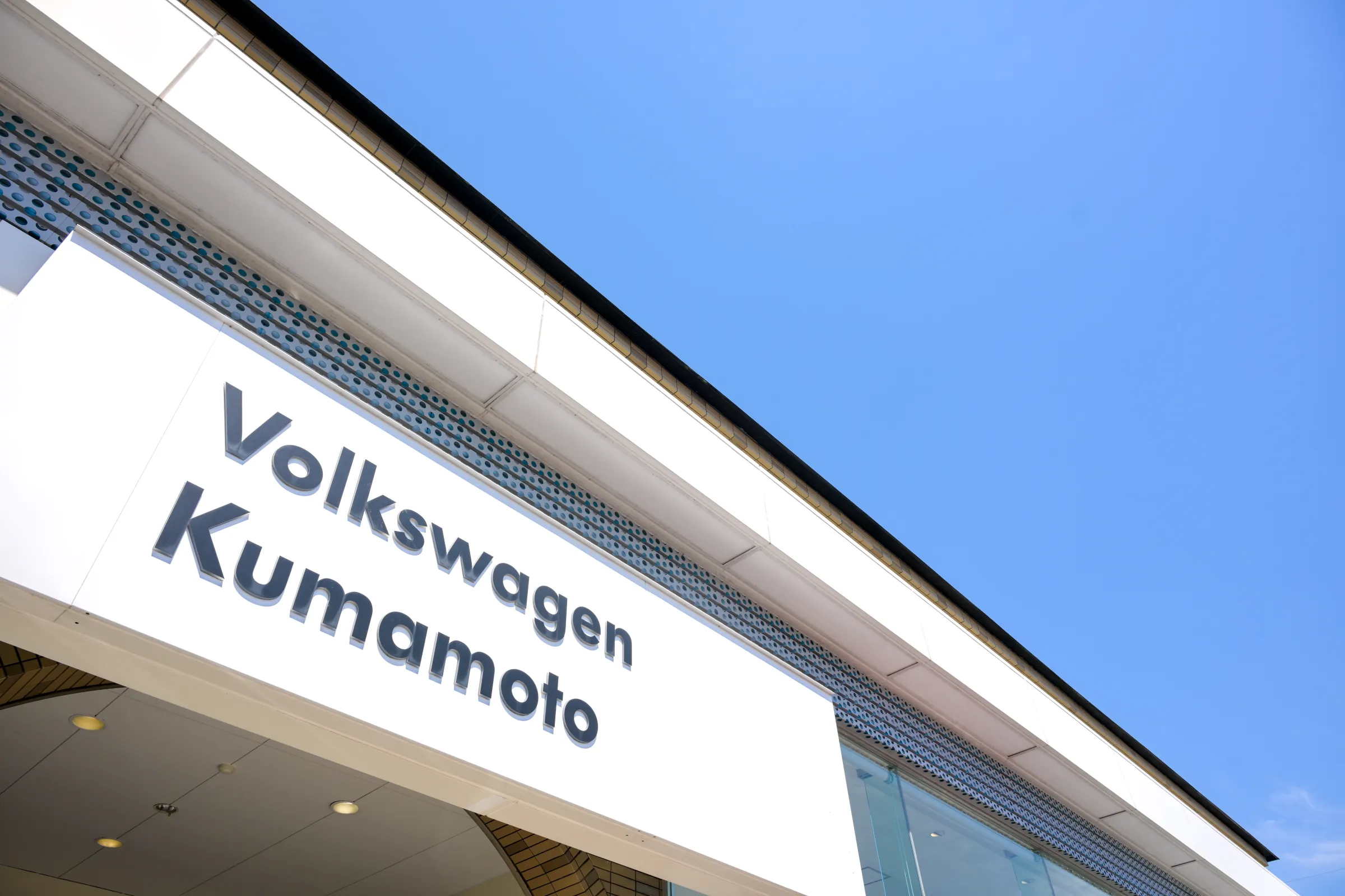 青空の下に掲げられたVolkswagen熊本の店舗看板